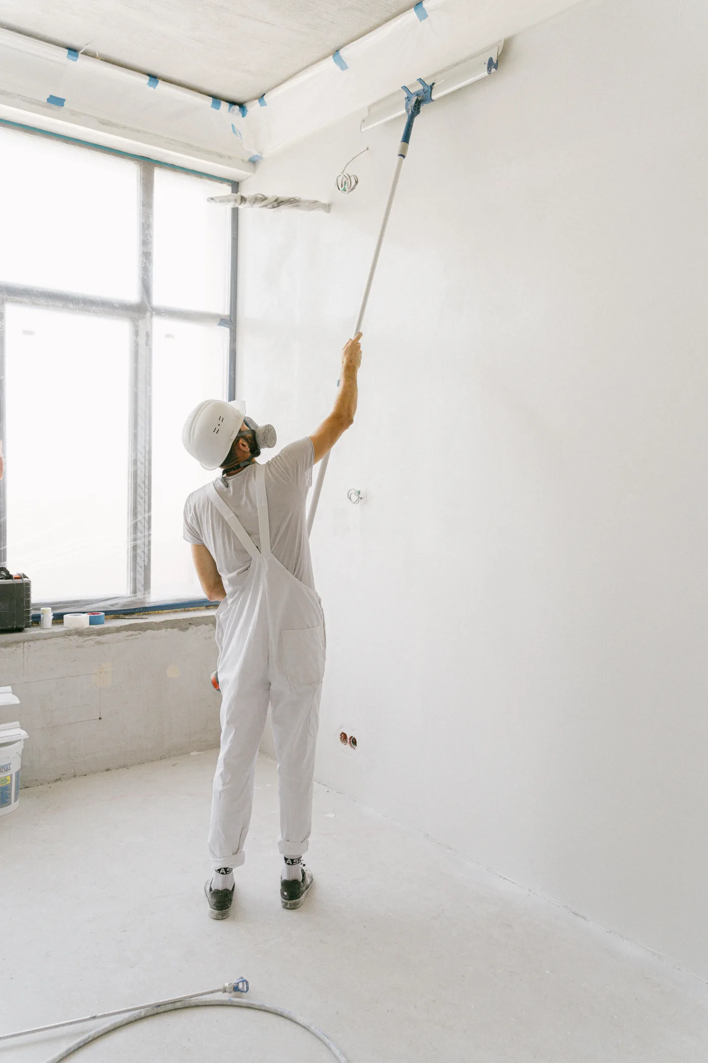 Stock photo of a professional painter in workwear applying paint to an interior wall